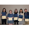 Five students smile while holding award certificates.