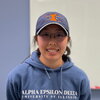 A smiling woman wearing glasses and a baseball cap.