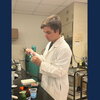 A man in a white lab coat using a pipette