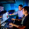 Two men standing in front of a computer.