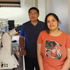 A man in a blue shirt and a woman in an orange shirt standing next to a microscope