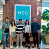 5 people standing in front of a sign reading, "MCB." 