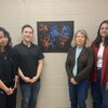 4 people standing next to a poster.