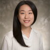 Woman with long black hair wearing white long sleeved shirt