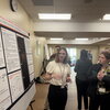 Undergraduate presents research poster to attendee of neuroscience conference