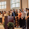 students stand on stage while being recognized for their academic achievements