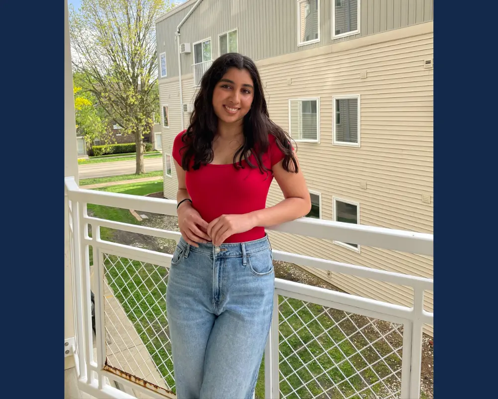 A woman with dark hair stands on a balcony.