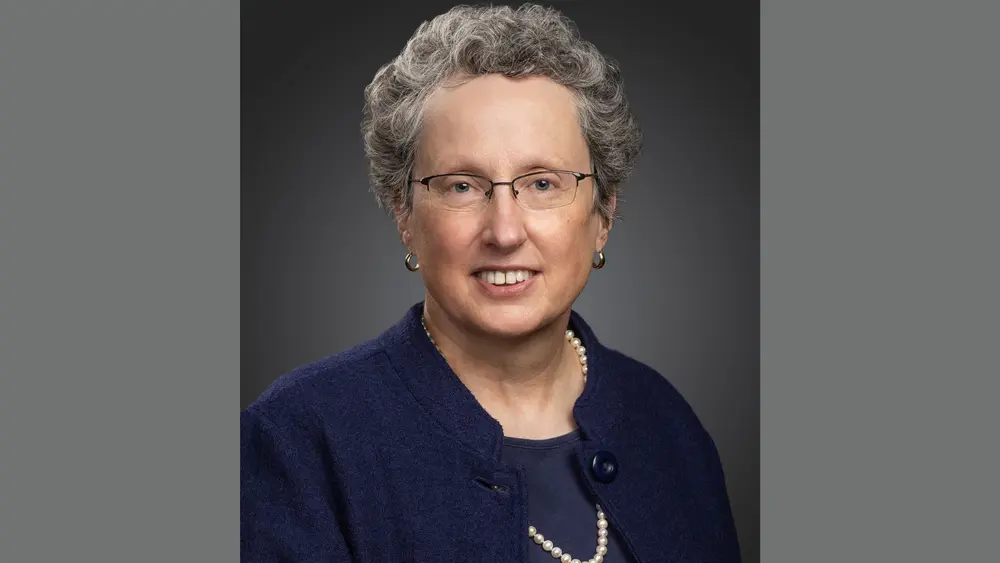 Headshot of woman with short grey hair and wearing navy sweater set