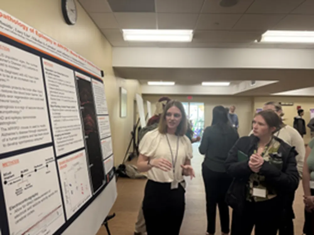 Undergraduate presents research poster to attendee of neuroscience conference