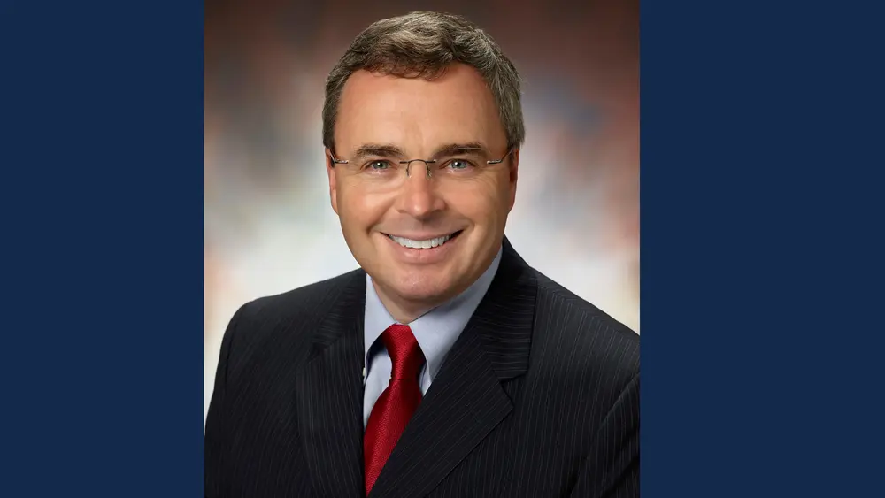 Guy Padbury in a dark suit and red tie