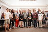 Roughly a dozen new faculty members in the College of LAS stand together for a group photo indoors.