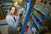 Stefanie Eben looks up at the camera with a smile. She is standing next to an anaerobic chamber. 