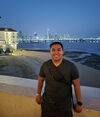smiling young man stands in front of ocean 