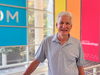 Man in blue polo stands in lab atrium with colorful signs in background