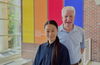 Man and woman stand and smile while in the atrium of laboratory building