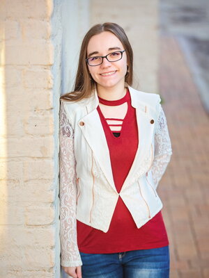 Emily Davis stands outside by a brick wall. 