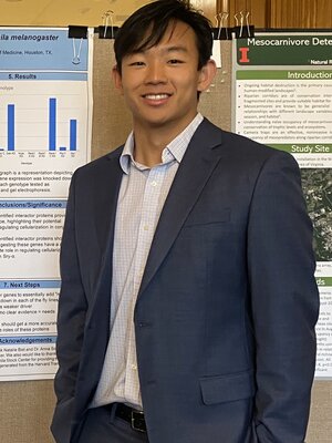 Matthew Kim stands next to a research presentation poster.