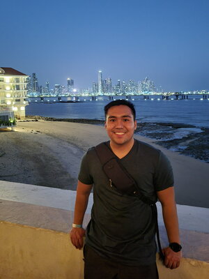 smiling young man stands in front of ocean 